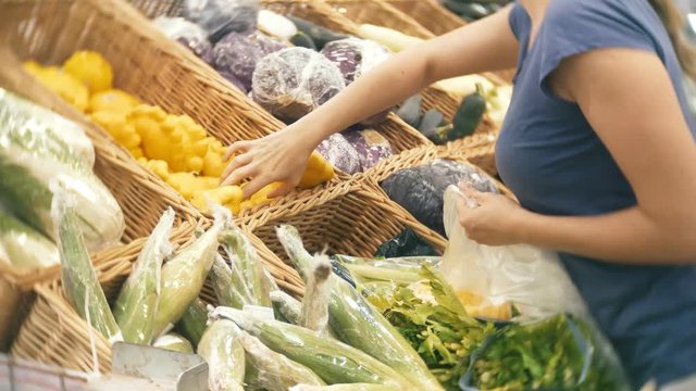A woman in a supermarket buying vegetables, pumpkin