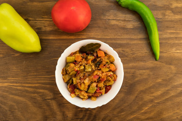 Homemade zucchini caviar with tomatoes, carrots and sweet peppers, whole fruits on a wooden background, top view.