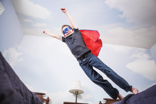 Boy super hero wearing cape and mask using imagination to fly