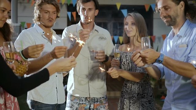 Happy group of people making a toast, having fun, smiling, enjoying picnic party with drinks outdoors together. Young friends celebrating birthday. Holiday celebration festive party. Teenage lifestyle