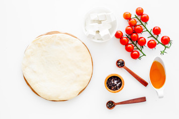 Ingredients for cooking vegetarian pizza. Rolled pizza dough, cherry tomatoes, olive oil, cheese mozzarella, spices on white background top view mockup