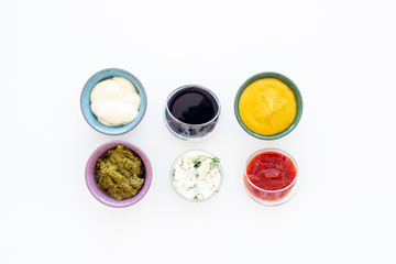 Set of sauces. Ketchup, mayonnaise, mustard, soy sauce, barbecue sauce, pesto, mustard, sour with greenery on white background top view copy space