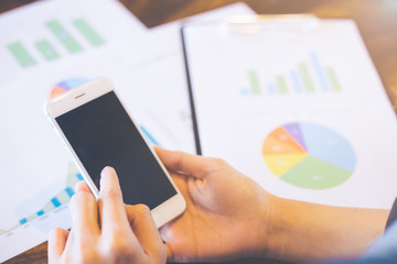 Business work with mobile phones on statistics and business graphs.