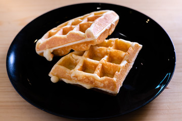 woman hands prepare waffle for serving process.waffle made from dough and batter.tasty dessert sweets waffle served on daylight in cafe bokeh background.waffle with strawberry on black plate.