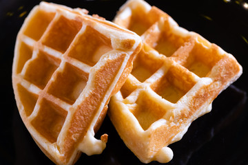 woman hands prepare waffle for serving process.waffle made from dough and batter.tasty dessert sweets waffle served on daylight in cafe bokeh background.waffle with strawberry on black plate.