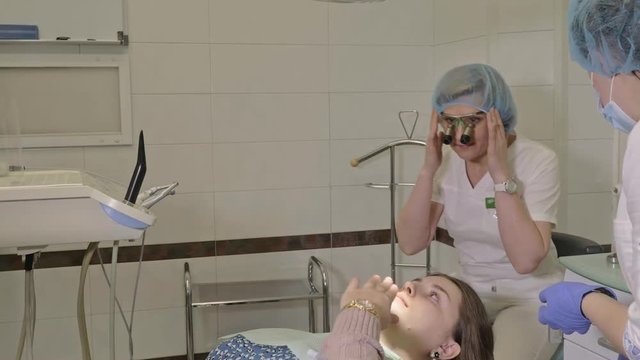 Woman at dentist clinic gets dental treatment to fill a cavity in a tooth. Dental restoration and composite material polymerization with UV light and laser. The doctor works with an assistant.