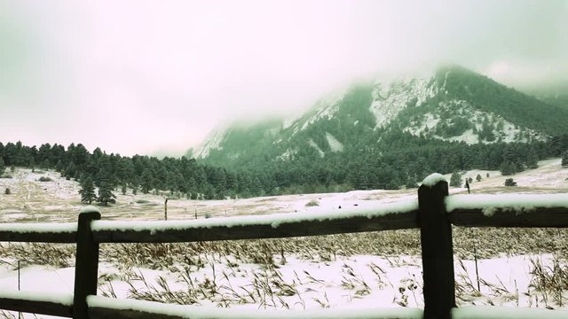 rural split rail fence frames a mountain range in the snow
