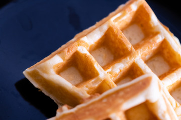woman hands prepare waffle for serving process.waffle made from dough and batter.tasty dessert sweets waffle served on daylight in cafe bokeh background.waffle with strawberry on black plate.