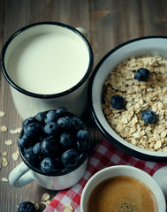 Healthy eating, food and diet concept - tasty oatmeal with berries and a mug of milk and a cup of coffee.Top view.