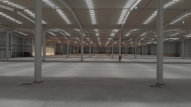 Aerial interior clip of an empty warehouse with camera moving forward.