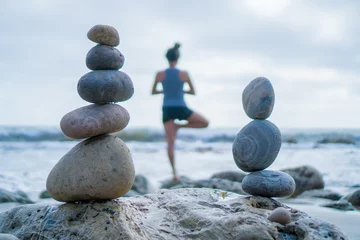 Fotobehang Zen Stenen Mooie meisjesboom poseert yoga aan de oceaan met stapelstenen  © Steven