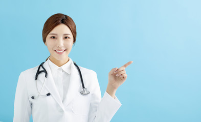 Smiling female doctor pointing with finger on blue background