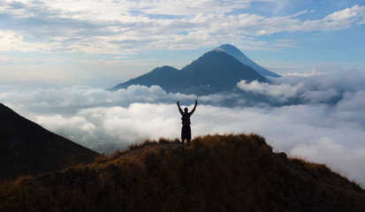  hiker person rising hand standing on walk way at volcano Batur, Bali island, Indonesia.