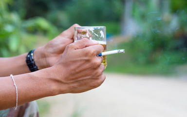 Hand with burning cigarette and hands holding up glasses of beer