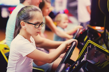 Cute girl plays a rifle shoots arcade in game machine at an amusement park.