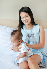 Mother is belching for infant baby after breastfeeding at bedroom. Focus at mom.