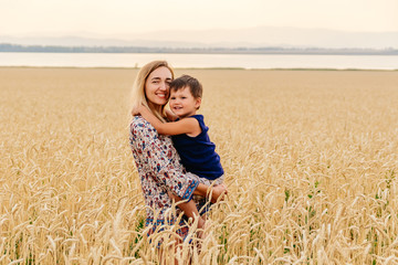 young beautiful mother with baby faces in wheat field