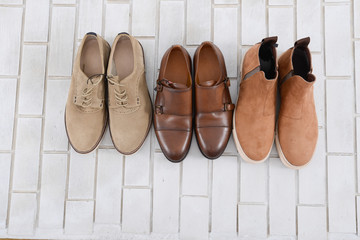 Set of mans three fashion shoes on white brick wall