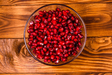 Seeds of the garnet fruit in glass bowl on wooden table. Top view