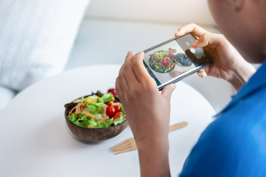 A woman is using smartphones to take photos to post a salad she made in her social.