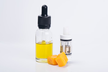 on a light background stands a bottle of yellow liquid for e-cigarettes, with a taste of candy