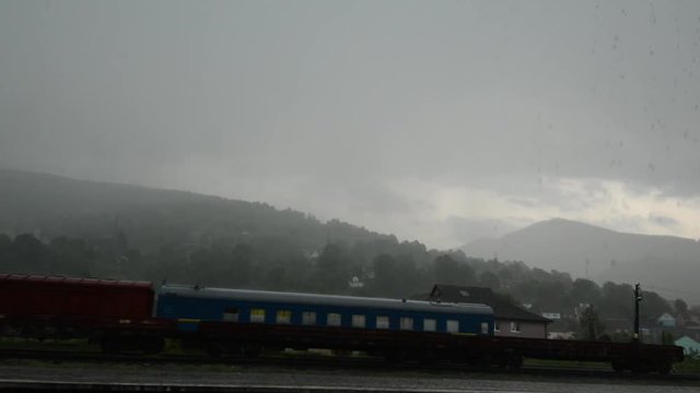 Old train stands on a countryside railroad station under havy rain. Nobody is on a station