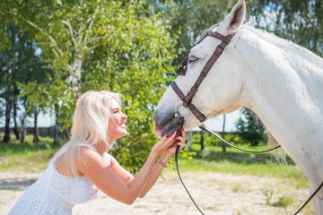 Beautiful american girl with a horse in the nature. Concept of horse and human. Portrait of young artistic woman walking with horse outdoors 