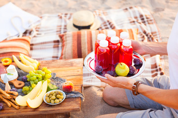 Picnic on the beach at sunset in the style of boho. Concept outdoors evening healthy dinnner with fruit and juice © yatcenko
