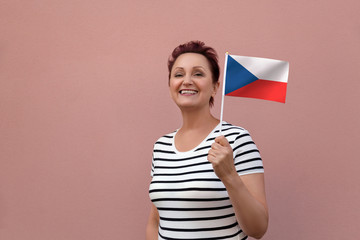 Czech flag. Woman holding the flag of the Czech Republic. Nice portrait of middle aged lady 40 50 years old with a national flag over pink wall background.