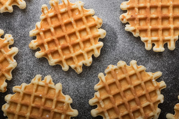 Belgian waffles with sugar powder on the black table. Baking dessert. Healthy breakfast.