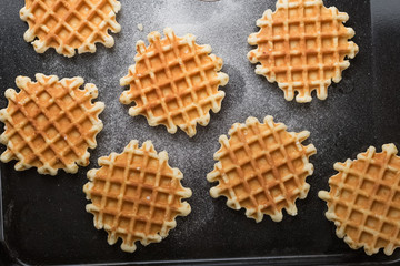 Belgian waffles with sugar powder on the black table. Baking dessert. Healthy breakfast.