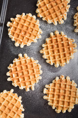 Belgian waffles with sugar powder on the black table. Baking dessert. Healthy breakfast.