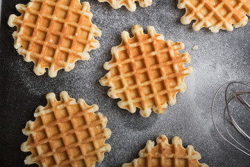 Belgian waffles with sugar powder on the black table. Baking dessert. Healthy breakfast.