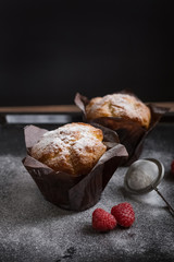 Tasty cupcake with raspberry and sugar powder on the dark background. Homemade dessert. 