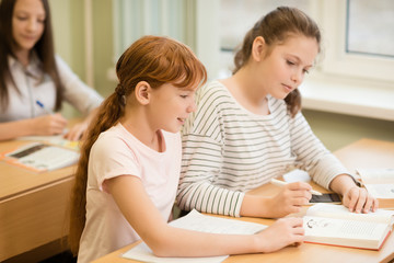 3 student girls are sitting at a Desk