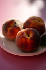Three whole ripe peaches fruits close up on pink board and table