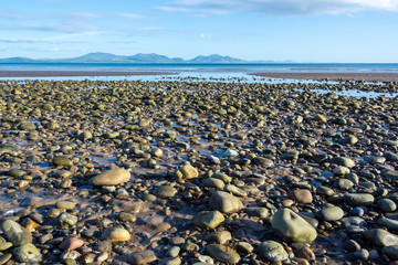 Pebbles on a beach of Anglesey and mountains of Snowdonia across the Menai Strait