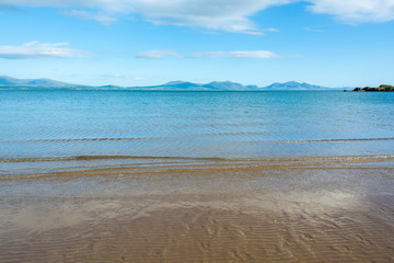 Gentle waves on sandy beach of Anglesey and mountains of Snowdonia across the Menai Strait - 2