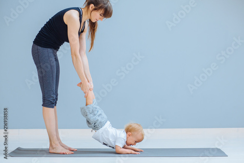 Happy Laughing Mother Doing Gymnastic For Toddler Baby Boy On Yoga