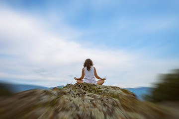young woman meditating on a rock. tranquility and privacy in the mountains. Travel and tourism