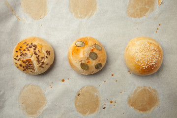 Homemade burger bun on bakery parchment . Food photography, concept of homemade fresh bakery. Rolls with sesame seeds hamburger with sesame, pumpkin, flax, sunflower seeds