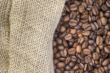 Coffee beans in coffee burlap bag on wooden surface