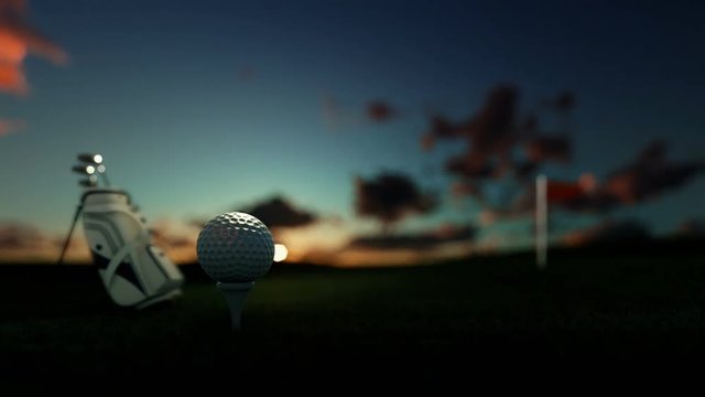 Golf clubs and golf ball on tee with red flag against beautiful timelapse sunrise