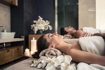 Poster Im Rahmen Young man and woman lying down on massage beds at Asian luxury spa and wellness center © Kzenon