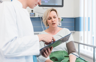 Doctor discussing treatment results with patient in intensive care unit of hospital 