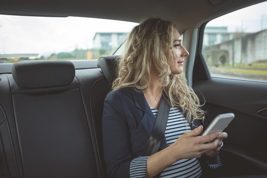 Woman holding smartphone while travelling in car
