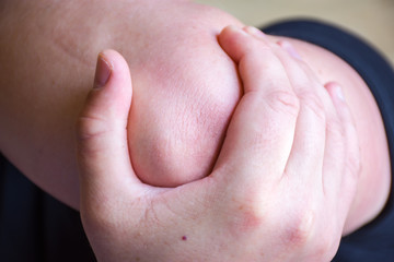 Fototapeta premium Person or patient keeps to elbow with palm of the other hand due to severe pain in the elbow joint, trauma or injury, fracture, rupture or sprain, as symptom of chronic joint disease recurrence 