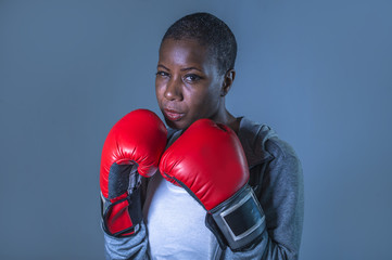  face portrait of young angry and defiant black afro American sport woman in boxing gloves training...
