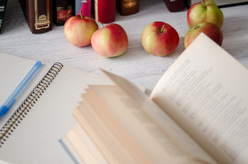 Knowledge Day. Open book, notebook, pen and ripe red apples on the wooden table.