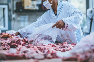 Photo sur Plexiglas Viande L& 39 emballeur de viande crue et l& 39 abatteur travaillent dans l& 39 abattoir.